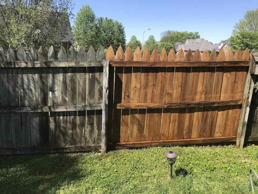Wood fence half cleaned showing gray before and brown after